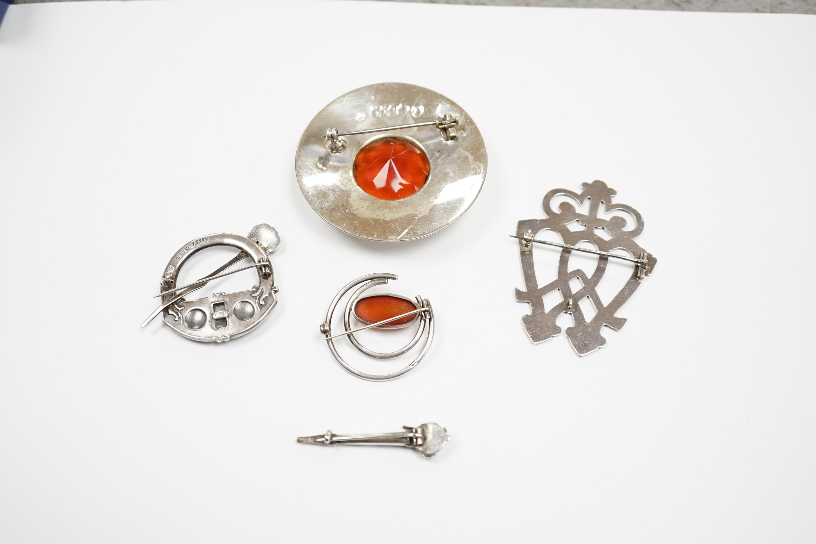 A 1950's Scottish silver and citrine coloured paste set circular brooch, 68mm, an Edwardian silver Celtic style brooch and three other white metal brooches, including Scottish hardstone set.